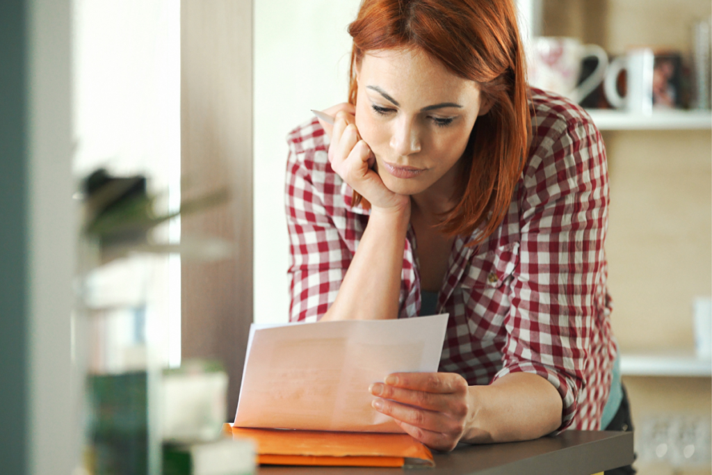 a woman looking worryingly at a paper bill