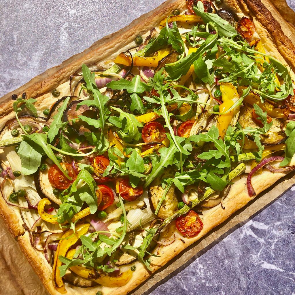 Baked puff pastry with roasted vegetables and rocket served on baking paper