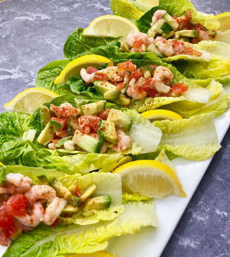 Platter of prawn cocktail lettuce boats topped with cayenne pepper and lemon wedges