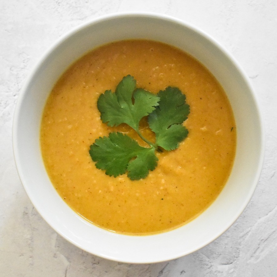 Bowl of curried butternut squash and yellow split pea soup garnished with fresh coriander