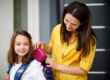 a mum puts a lunchbox into her daughter's school bag