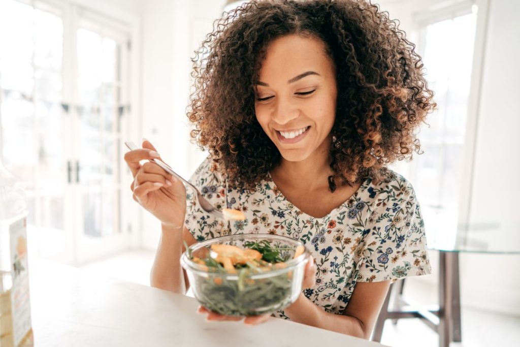 woman eating a salad and smiling