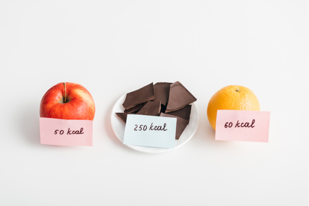 an apple, chocolate and orange with calorie labels