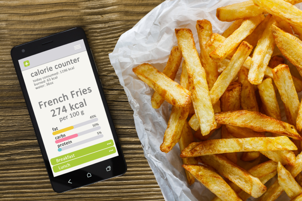 a portion of french fries next to a mobile phone with a calorie counter app