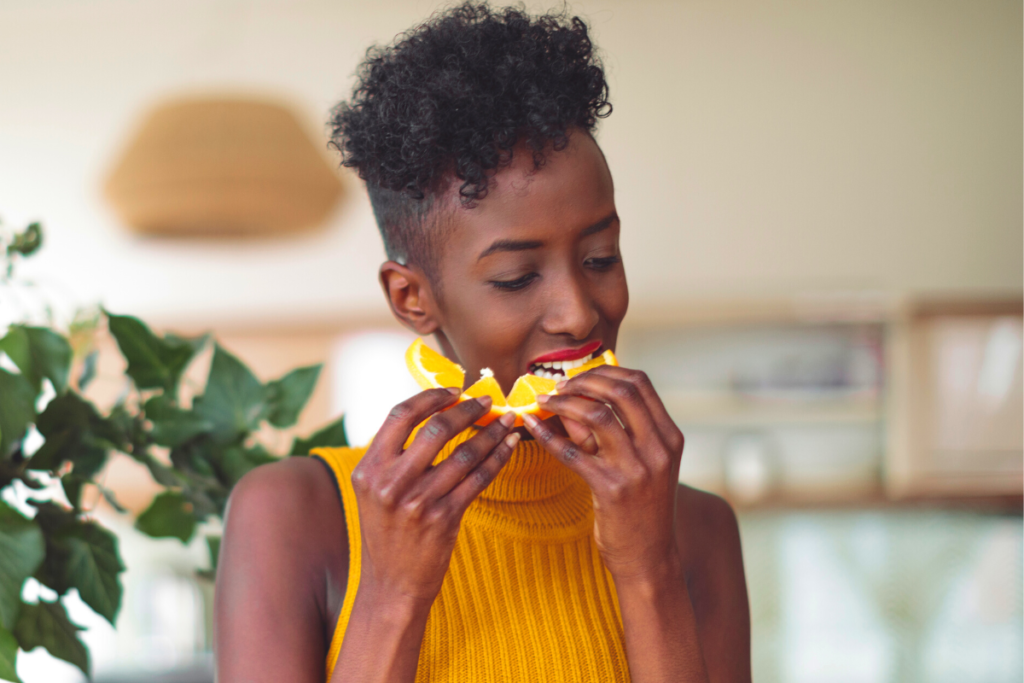 a woman biting into a slice of orange