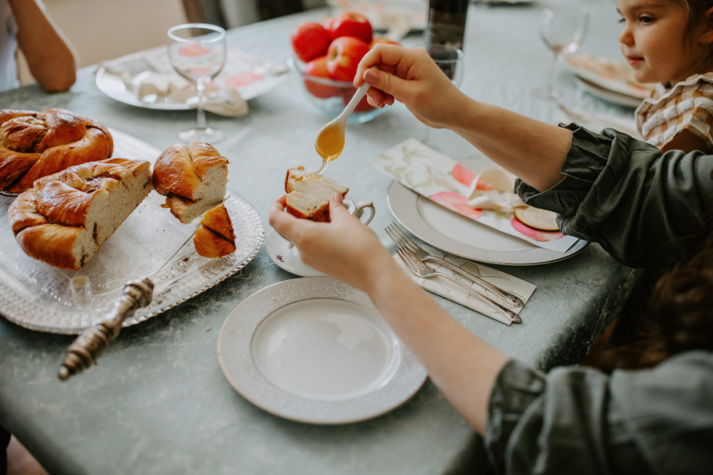 a woman's hands pouring honey over a piece of bread