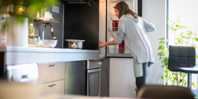 woman opening fridge to find ingredients