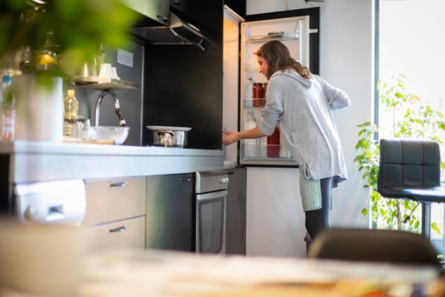 woman opening fridge to find ingredients