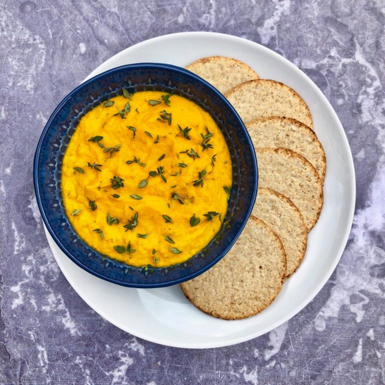 Carrot and thyme dip in a bowl topped with fresh thyme leaves, served with oatcakes